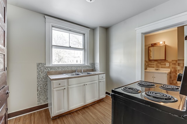 kitchen featuring white cabinets, black range with electric stovetop, light countertops, light wood-style floors, and tile walls