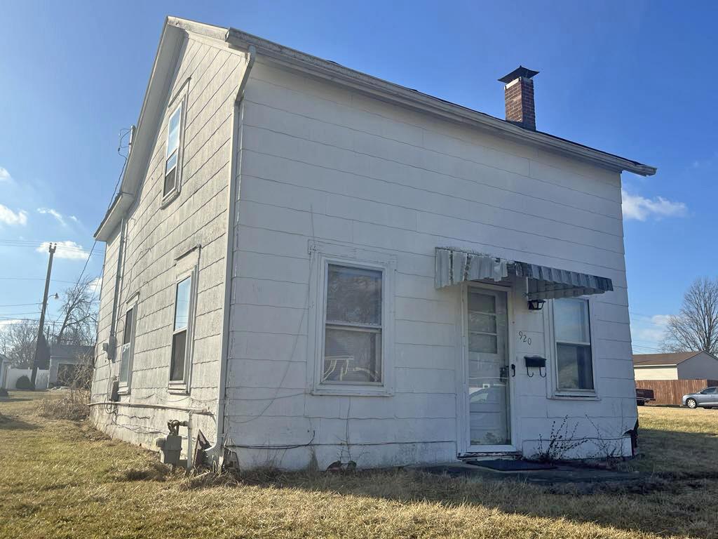 back of property with a lawn and a chimney