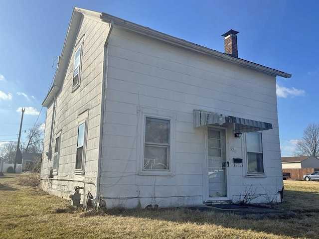 back of property with a lawn and a chimney