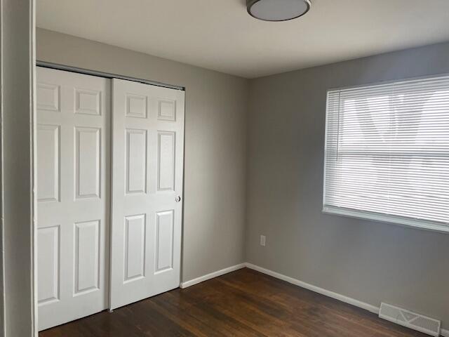 unfurnished bedroom with dark hardwood / wood-style floors and a closet