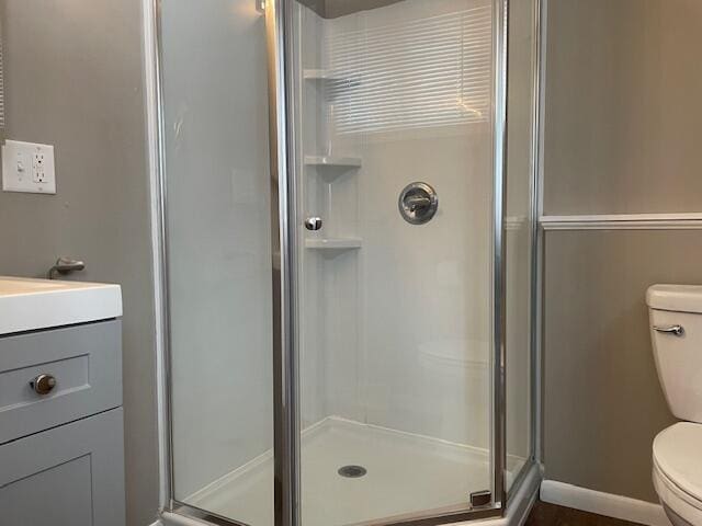 bathroom featuring wood-type flooring, toilet, a shower with door, and vanity