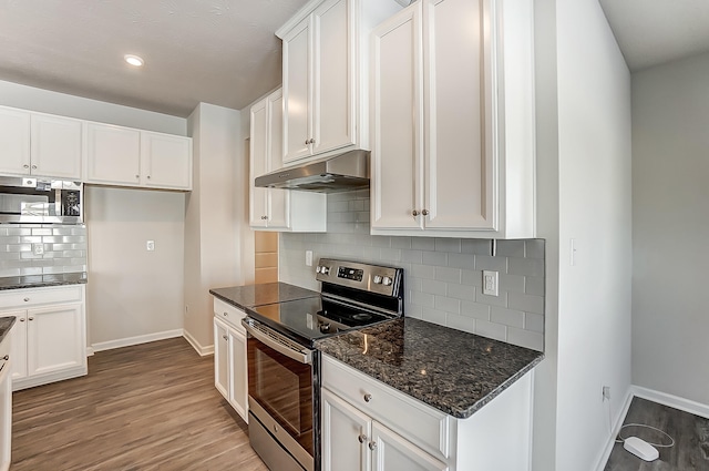 kitchen with appliances with stainless steel finishes, white cabinets, and backsplash