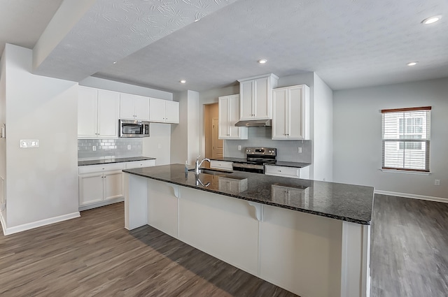 kitchen with a breakfast bar, sink, dark stone countertops, stainless steel appliances, and white cabinets