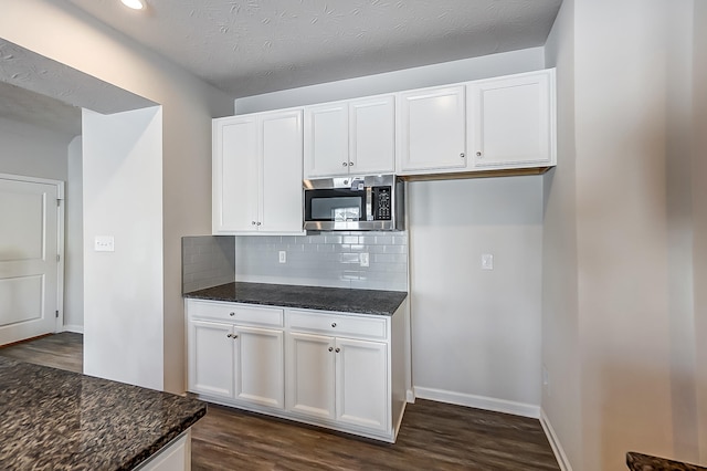 kitchen with dark hardwood / wood-style floors, dark stone countertops, white cabinets, and decorative backsplash