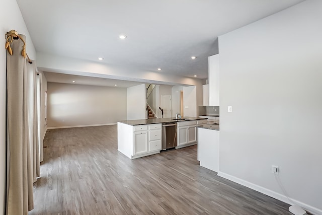 kitchen featuring dishwasher, white cabinetry, sink, light hardwood / wood-style floors, and kitchen peninsula