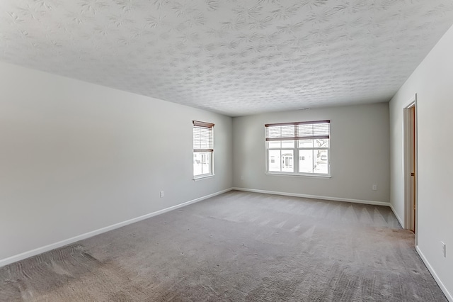 empty room with light colored carpet and a textured ceiling