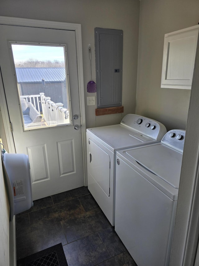 clothes washing area featuring stone finish flooring, washer and clothes dryer, cabinet space, and electric panel