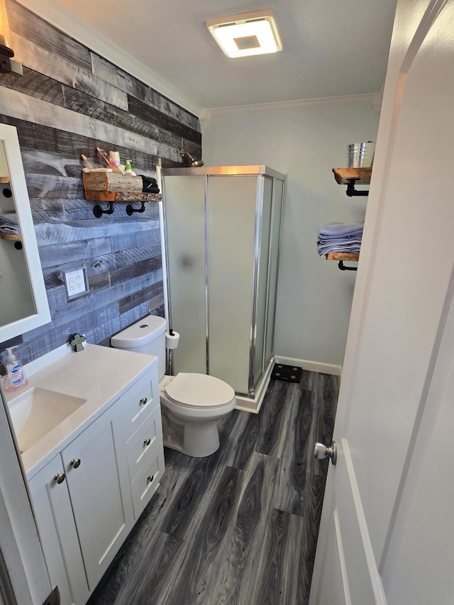 full bathroom with toilet, wood finished floors, vanity, ornamental molding, and a stall shower