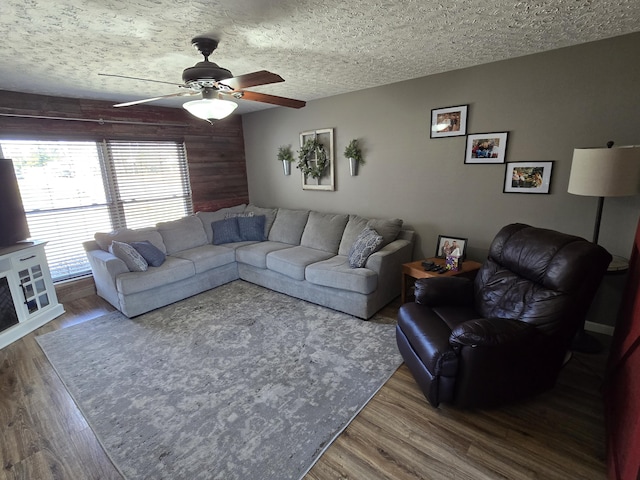 living room featuring ceiling fan, a textured ceiling, and wood finished floors