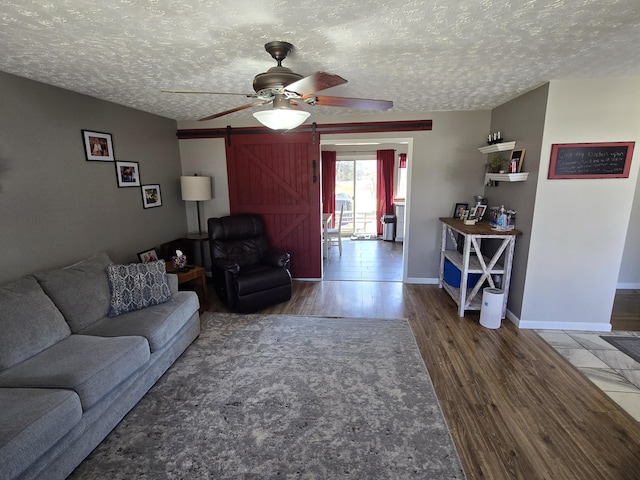 living area featuring a barn door, a textured ceiling, and wood finished floors