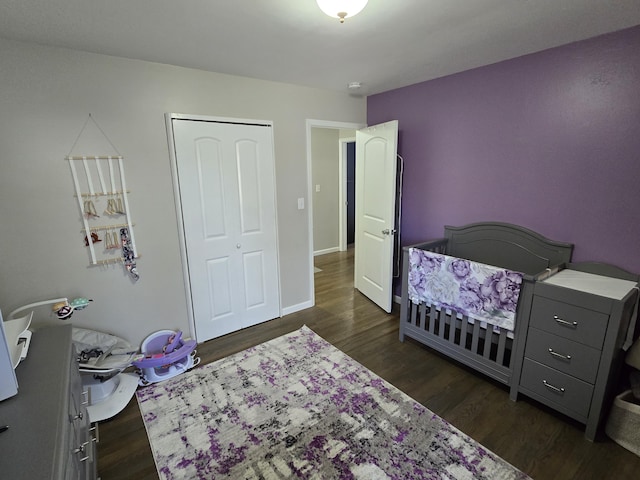 bedroom with dark wood-type flooring, a closet, and baseboards