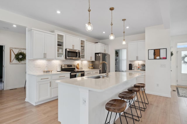 3600 Magnolia Trace Dr, Bellbrook, OH 45305 - kitchen with appliances with stainless steel finishes, a sink, light wood-type flooring, light countertops, and a breakfast bar