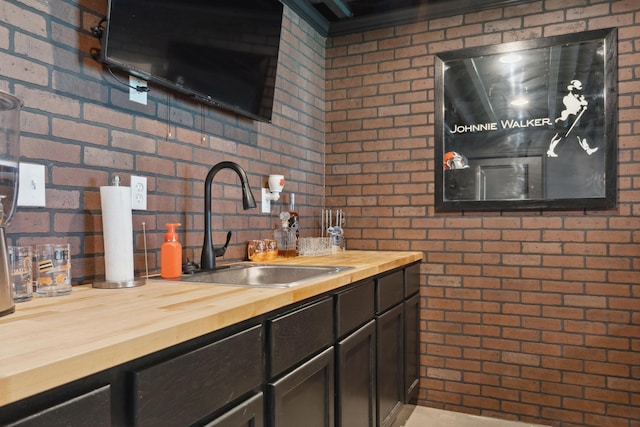 3600 Magnolia Trace Dr, Bellbrook, OH 45305 - kitchen featuring butcher block countertops, a sink, brick wall, dark brown cabinetry, and decorative backsplash