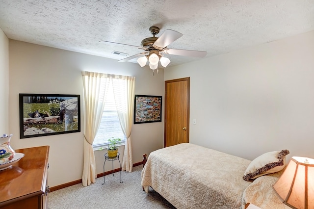 bedroom with a textured ceiling, baseboards, visible vents, and light carpet