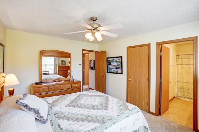 bedroom featuring a textured ceiling, ensuite bath, a closet, light colored carpet, and ceiling fan