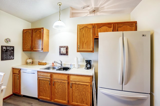 kitchen with visible vents, brown cabinets, a sink, white appliances, and light countertops