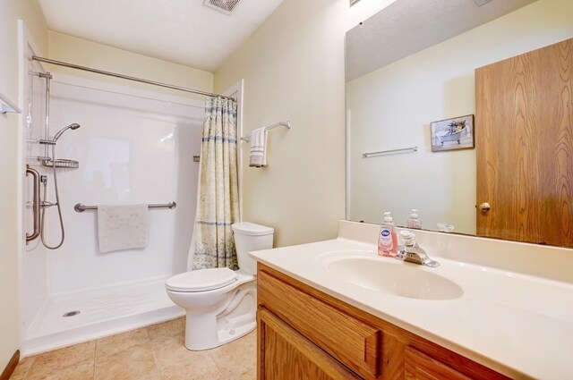 bathroom featuring tile patterned floors, a shower with curtain, toilet, and vanity