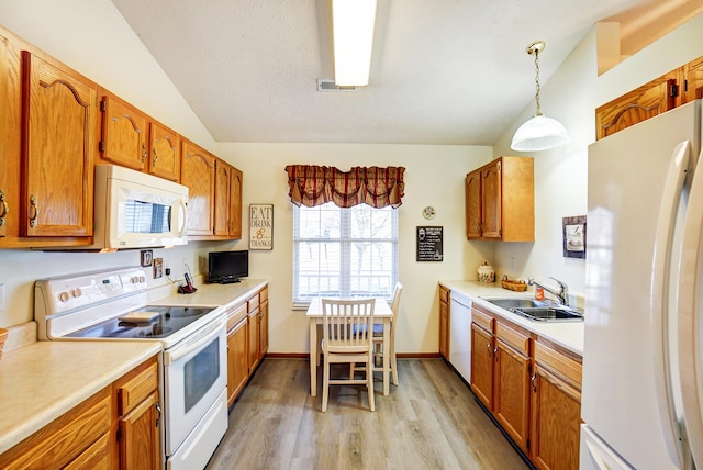 kitchen with white appliances, light countertops, lofted ceiling, and a sink