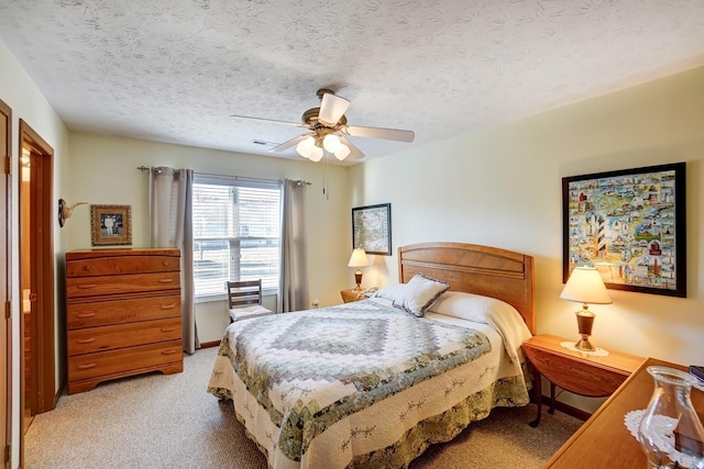 bedroom with light carpet, visible vents, a textured ceiling, and a ceiling fan