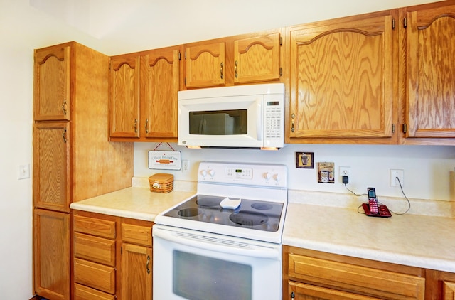 kitchen with white appliances, brown cabinetry, and light countertops