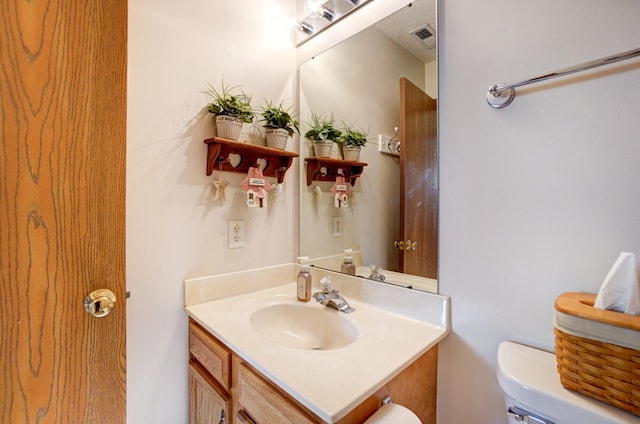 bathroom with vanity, toilet, and visible vents