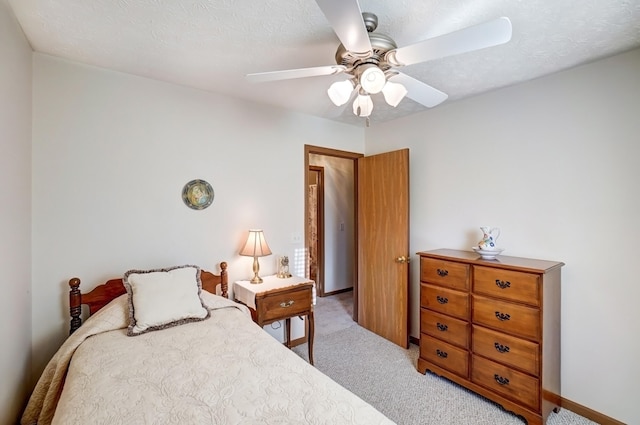 bedroom with a textured ceiling, ceiling fan, baseboards, and light carpet