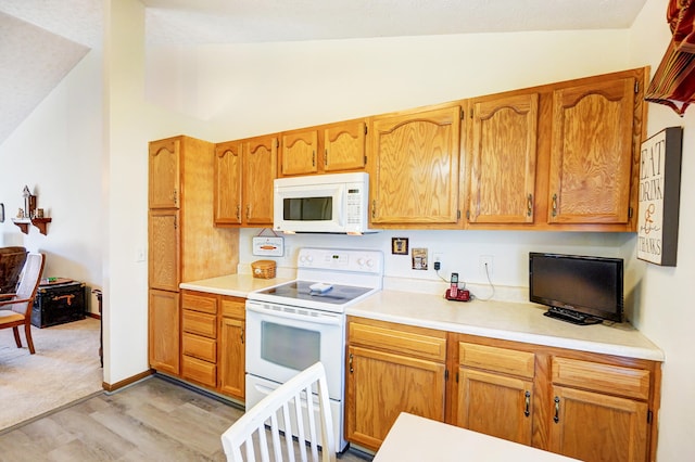 kitchen featuring white appliances, light countertops, light wood-type flooring, and vaulted ceiling