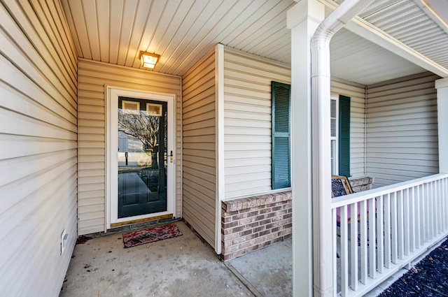 entrance to property featuring a porch and brick siding