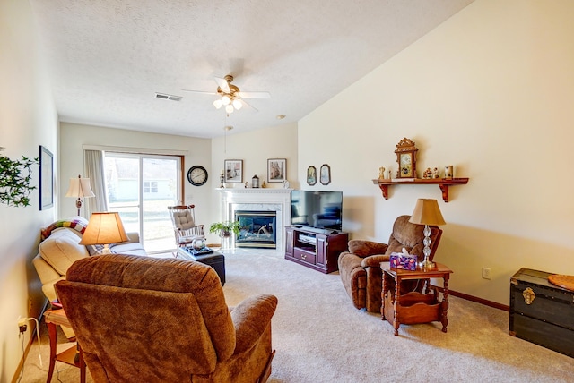 carpeted living room with a high end fireplace, visible vents, ceiling fan, vaulted ceiling, and a textured ceiling