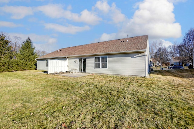 rear view of house featuring a yard, a patio, and a shingled roof