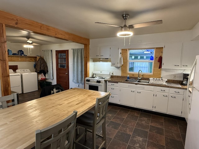 kitchen featuring white range with gas cooktop, sink, independent washer and dryer, and white cabinets