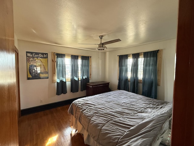 bedroom with ceiling fan, wood-type flooring, and multiple windows