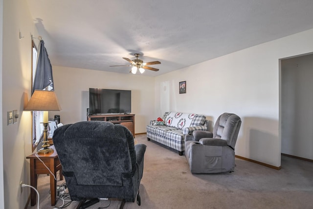 carpeted living area with a ceiling fan and baseboards