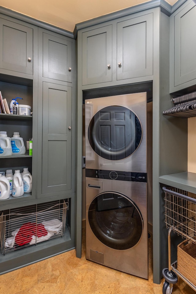 washroom featuring cabinets and stacked washer / dryer