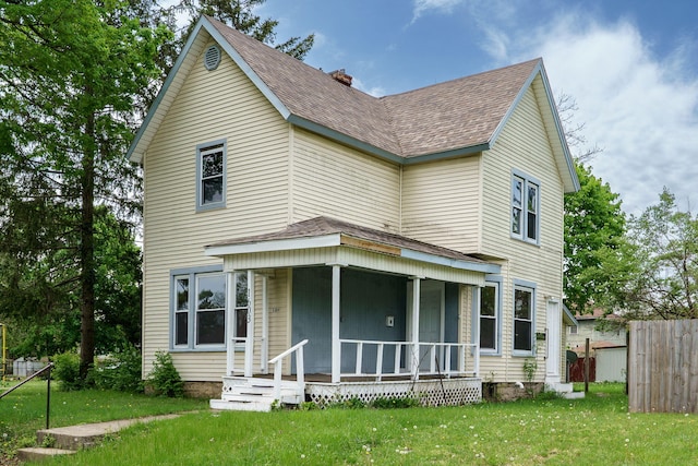 view of front of property with fence, covered porch, a front yard, roof with shingles, and a chimney