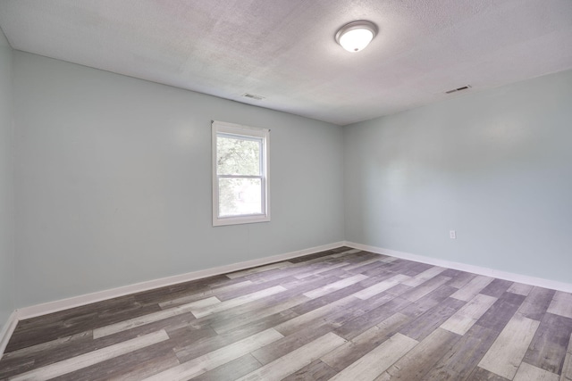 spare room with baseboards, wood finished floors, and visible vents