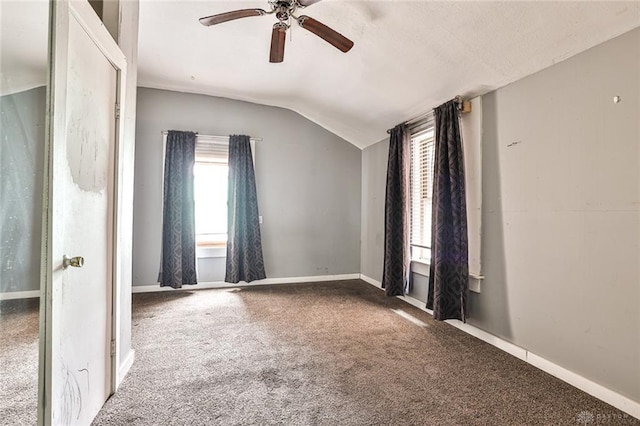 carpeted spare room with vaulted ceiling, ceiling fan, and baseboards