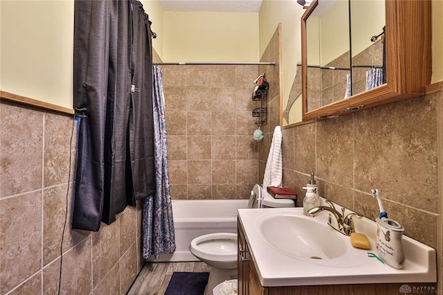 full bathroom featuring toilet, wood finished floors, shower / bath combo with shower curtain, tile walls, and vanity