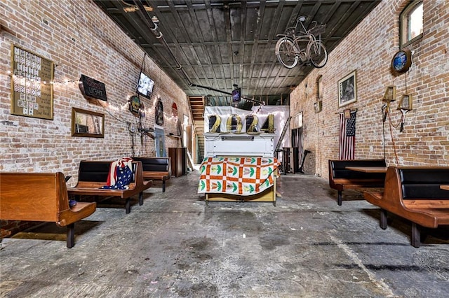 miscellaneous room featuring brick wall and a towering ceiling