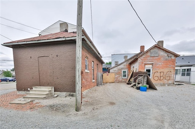 rear view of house featuring brick siding and fence