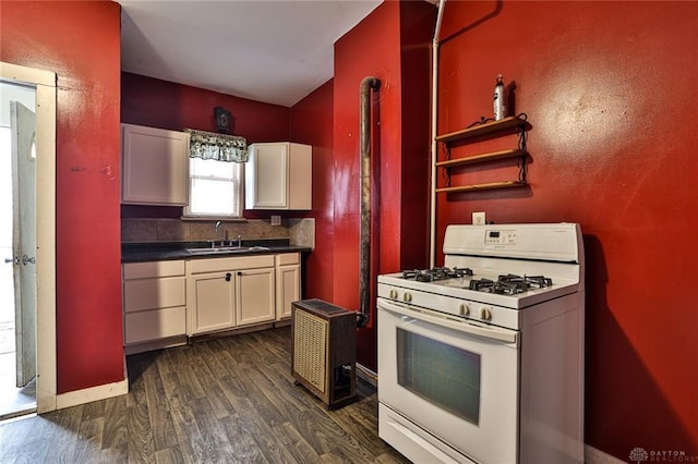 kitchen featuring a sink, white gas range, dark wood-type flooring, white cabinetry, and dark countertops