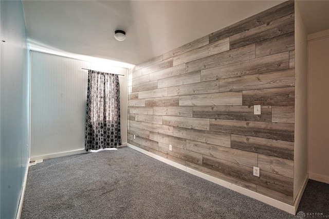 spare room with wood walls and carpet floors