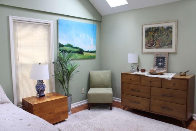 bedroom featuring lofted ceiling with skylight and light hardwood / wood-style floors