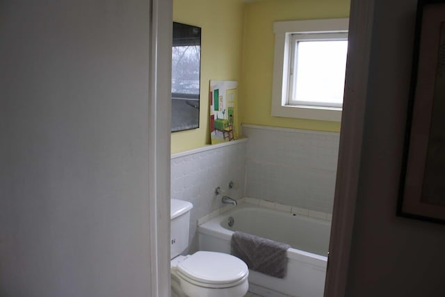 bathroom featuring toilet, tile walls, and a tub