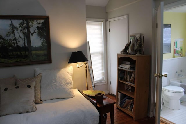 bedroom with multiple windows, wood-type flooring, and connected bathroom