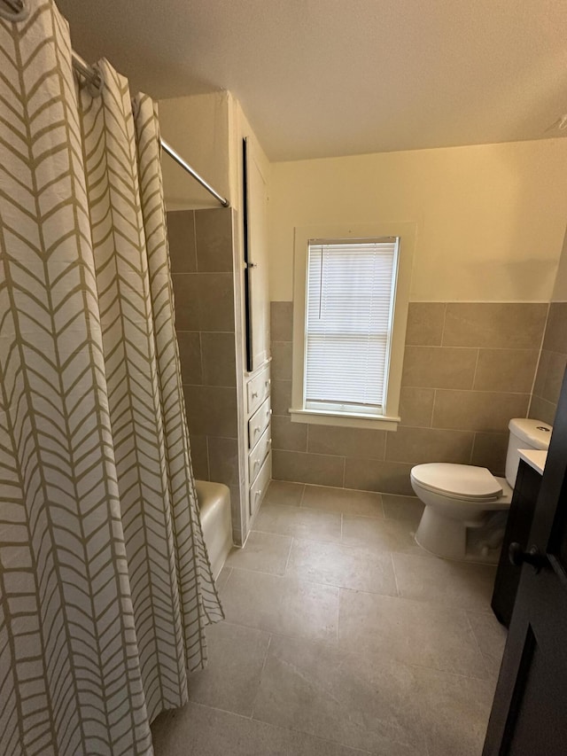 bathroom with tile walls, toilet, and shower / bath combo