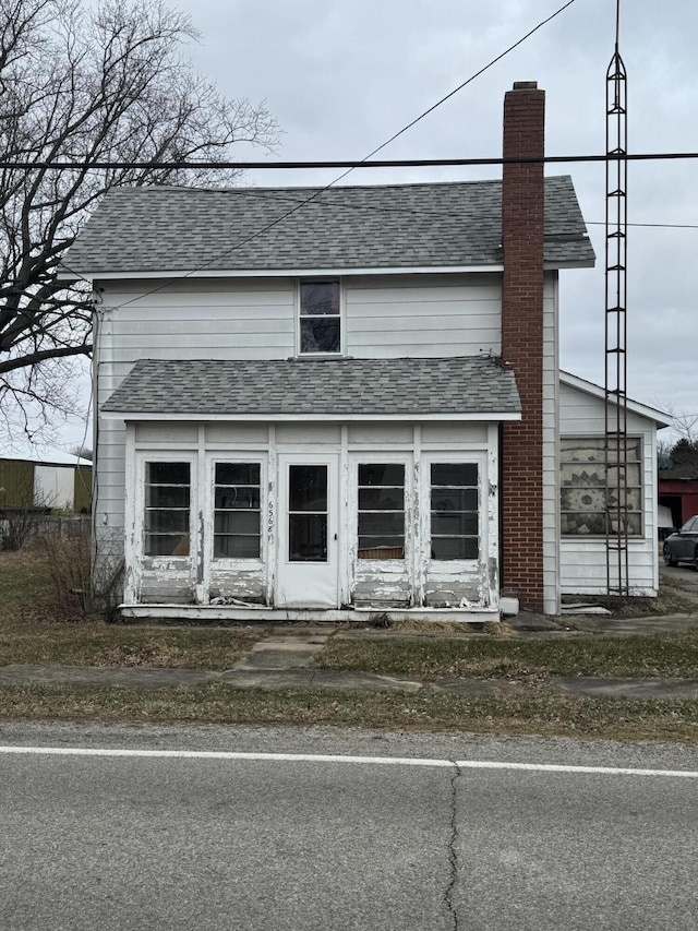 view of front of house with a chimney and roof with shingles