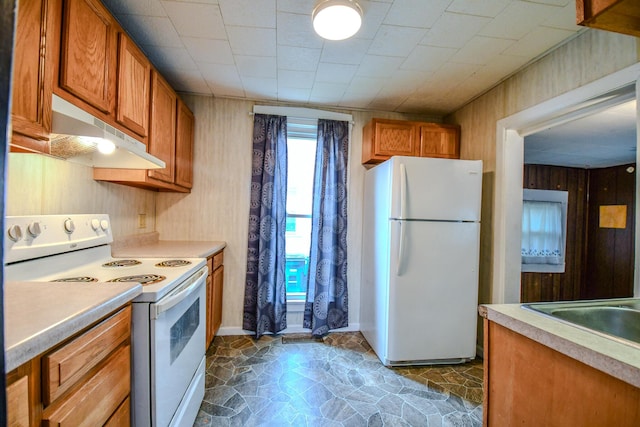 220 Williams St, Troy, OH 45373 - kitchen featuring white appliances, under cabinet range hood, brown cabinets, light countertops, and wood walls
