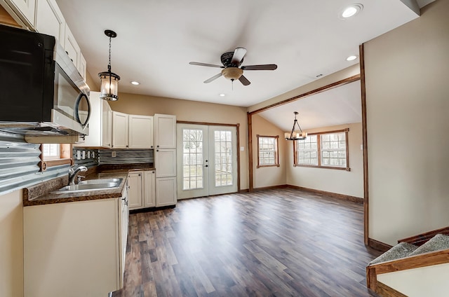 kitchen with a sink, stainless steel microwave, dark countertops, dark wood-style floors, and white cabinetry