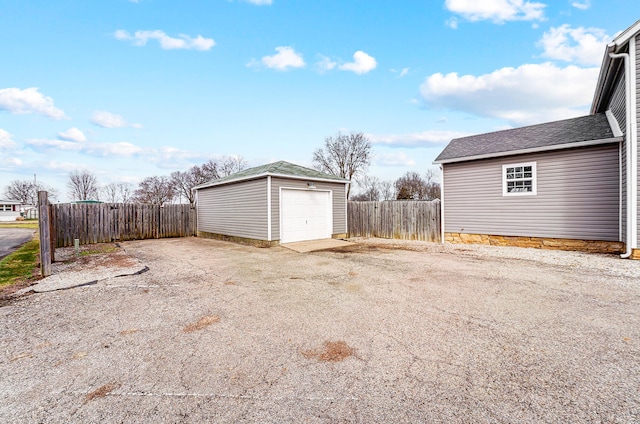 detached garage featuring driveway and fence